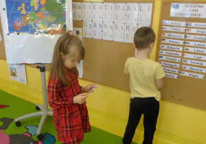 Dwoje dzieci przyczepia na tablicy nazwę kraju należącego do Unii Europejskiej.